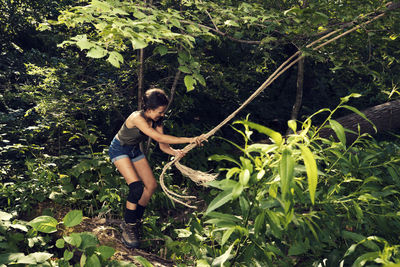 Girl playing with rope in forest