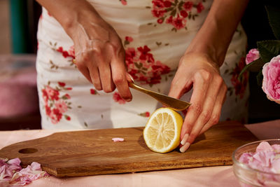 Woman adding drops of lemon to tea roses petals. homemade tea rose jam preparing with sugar, lemon