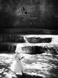 Digital composite image of woman with arms outstretched against wall