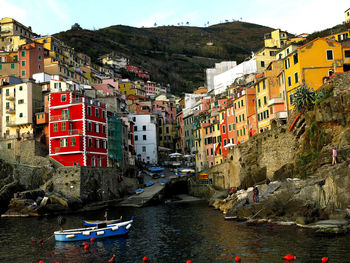 Buildings by river against sky in city