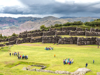 Group of people on mountain against cloudy sky