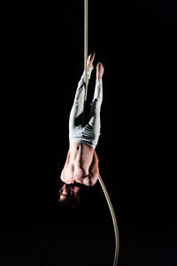 Midsection of man holding rope against black background