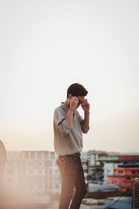 Young man using mobile phone against sky