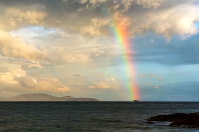 Scenic view of rainbow over sea against sky