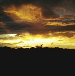 Silhouette landscape against dramatic sky during sunset