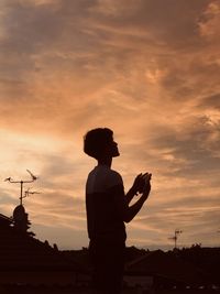 Silhouette man standing against orange sky