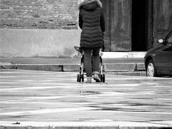 Low section of woman pushing baby stroller on road