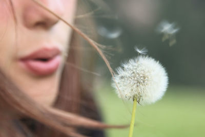 Close-up of young woman with dandelion flower
