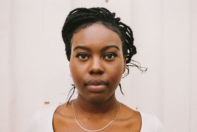 Close-up of young woman looking away against wall