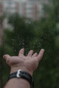 Cropped image of person hand on wet window during rainy season
