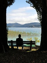 Man sitting on bench at lakeshore