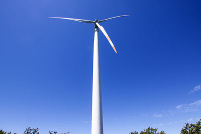 Low angle view of wind turbine against blue sky