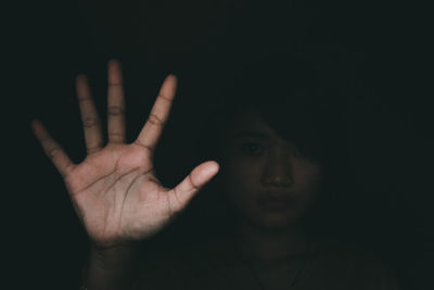 Portrait of young woman gesturing against black background