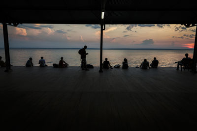 Silhouette people on beach against sky during sunset