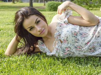 Portrait of beautiful young woman lying on grassy field