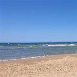 Scenic view of beach against clear blue sky