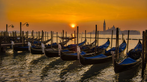 Boats moored at dock during sunset