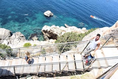 High angle view of family walking on steps against sea during sunny day