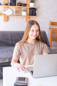 Portrait of smiling young woman using laptop on table