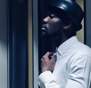 Side view of young man adjusting necktie