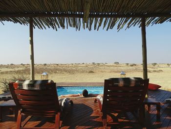 Man relaxing in swimming pool seen from gazebo at kalahari desert