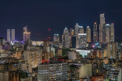 Illuminated buildings in city against sky at night