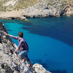 High angle view of man sitting on rock by sea