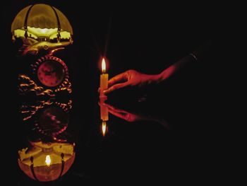 Person holding lit candles in the dark