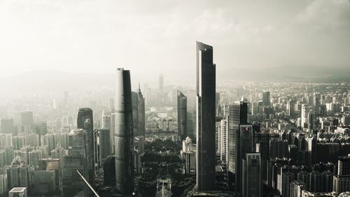 Skyscrapers amidst buildings against sky on sunny day in city