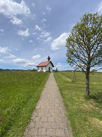 Footpath amidst field against sky