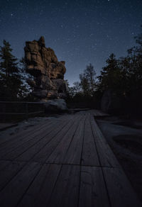 Walkway amidst trees against sky at night