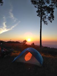 Tent on land against sky during sunset