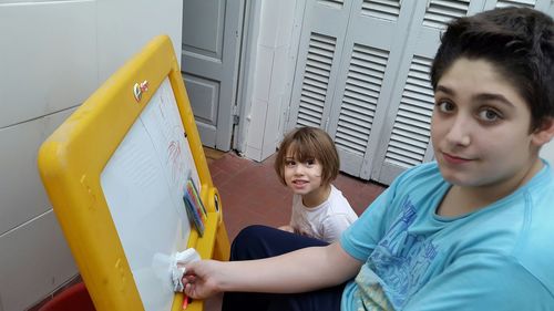 Portrait of happy girl watching his brother drawing