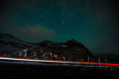 Light trails on road against sky at night