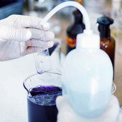 Cropped hand examining chemical on slide in laboratory