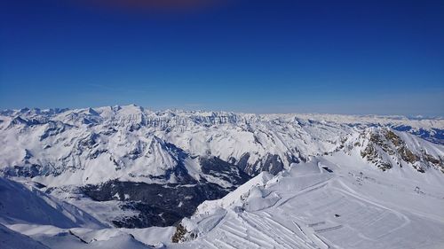 Scenic view of snowcapped mountains against clear blue sky