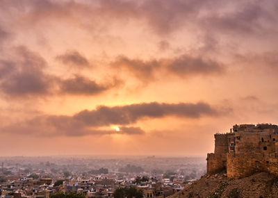 Buildings in city against sky during sunset