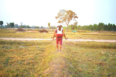 Rear view of woman walking on field