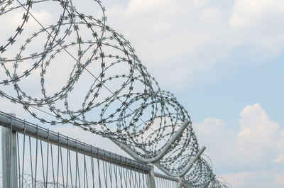 Low angle view of metal railing against sky