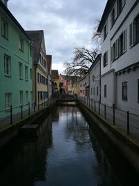 Canal amidst buildings in city against sky