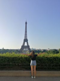 Rear view of woman standing against tower in city