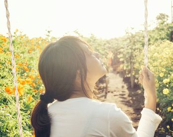 Rear view of woman swinging on field during sunny day