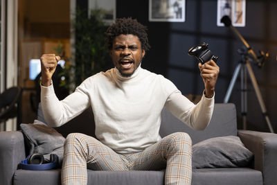 Young man using mobile phone while sitting on sofa at home