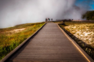 Footpath leading towards landscape against sky