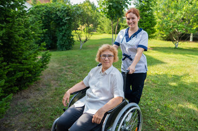 Portrait of smiling friends sitting on field