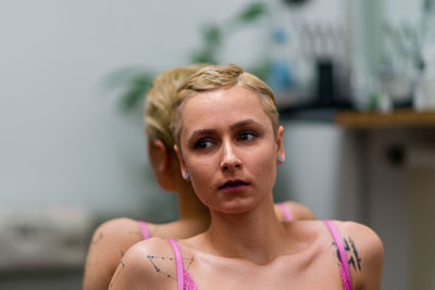 Portrait of young woman standing against wall