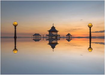 Reflection of pier against sky during sunset