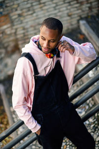 Young man using mobile phone while standing on railing