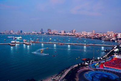 Aerial view of city by sea against sky