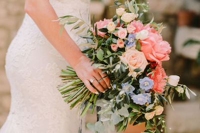 Midsection of bride holding bouquet of flowering plant